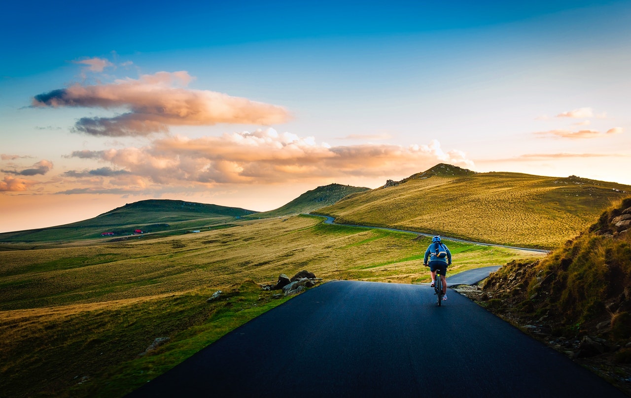 Migration to Kotest - a man on mountain road riding a bike towards rising sun